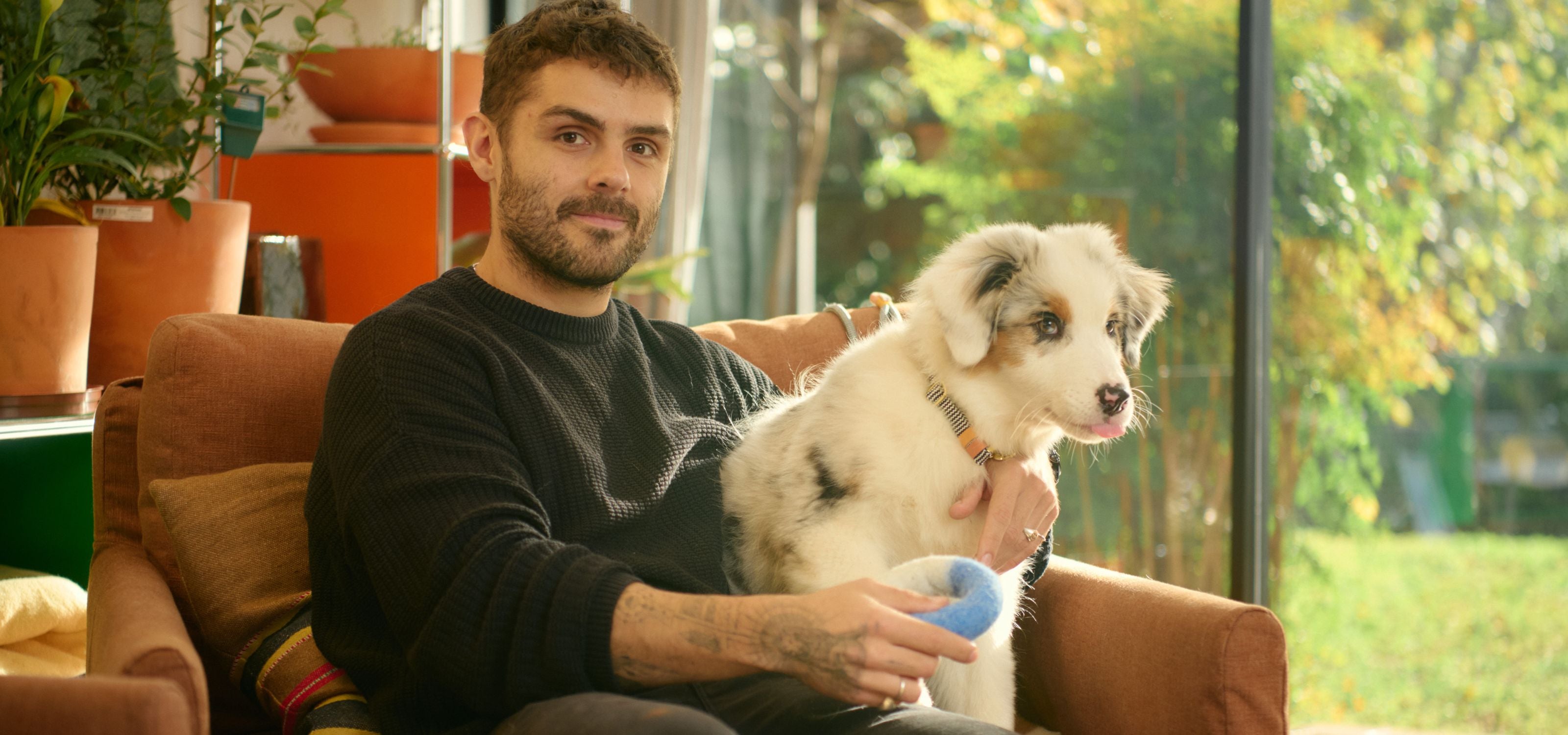Man sitting on a couch with a small dog in a home setting