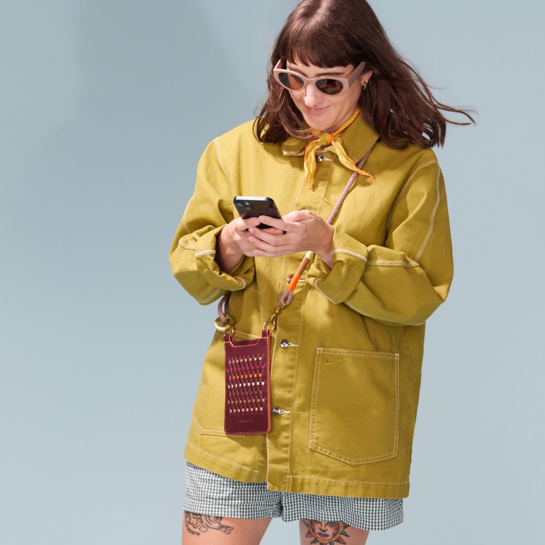 Woman in a yellow raincoat using a phone against a light blue background