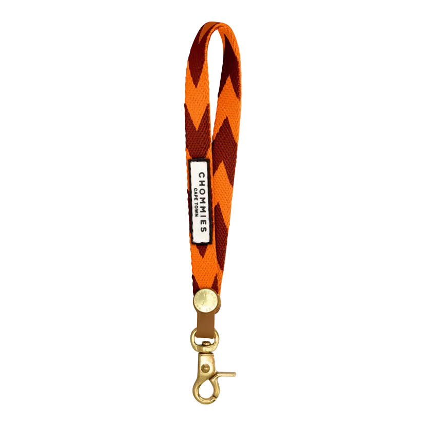 Orange and black zigzag patterned lanyard with a gold clip on a white background